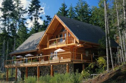 The exterior of a three story log cabin with wrap around deck and balcony above
