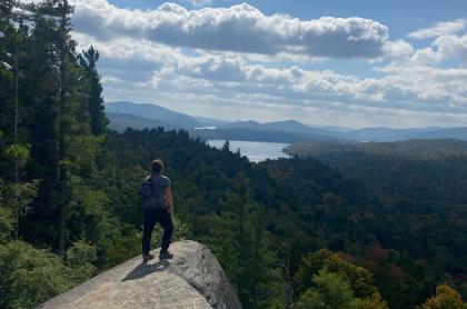 A hiker stands of a rock outcropping of Watch Hill.