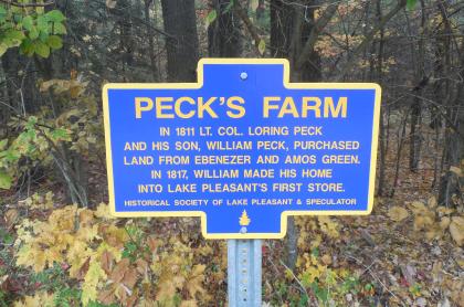 A blue historical sign for Peck's Farm
