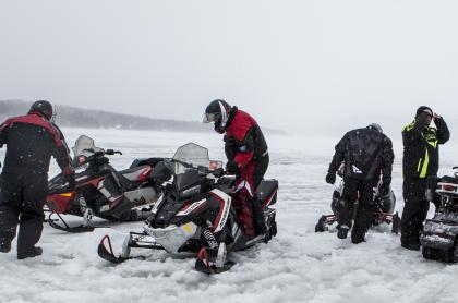 A group of snowmobilers stopped on the trail
