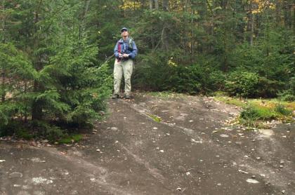 A man standing at the top of a sloped rock feature in the Moose River Plains.