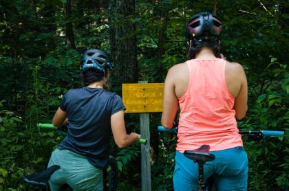 Two bikers looking at the sign for Kunjamuk Cave.