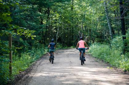 Two cyclists bike down a dirt road
