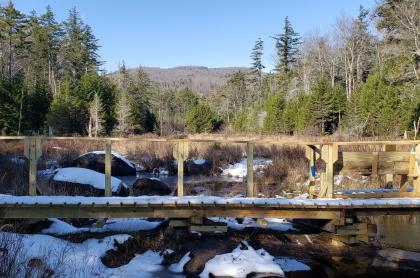A wooden bridge lightly covered in snow