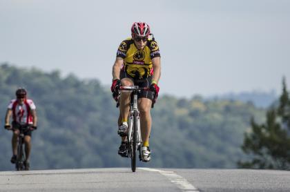 A cyclist cresting a hill on the road.