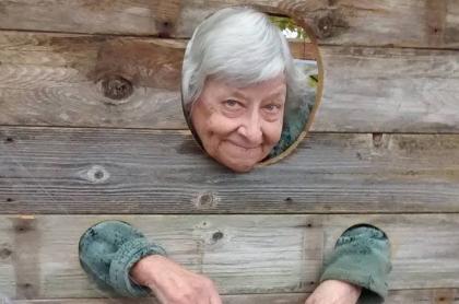 An older woman in the wooden stocks.