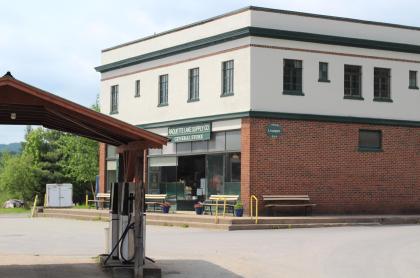 The exterior of a the two story brick and rendering building with gas pumps and ample parking.
