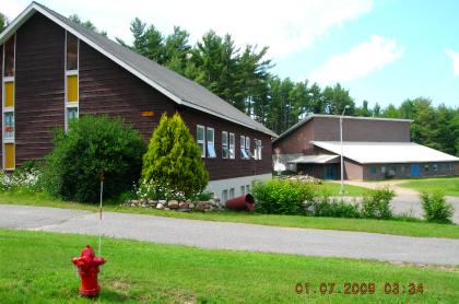 Exterior view of the lush grass and tall glass windows on the brown church.