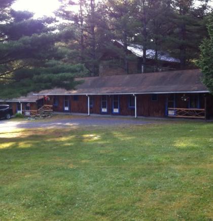 The large lawn and exterior of the brown building and white trim of the Blueberry Hill Motel