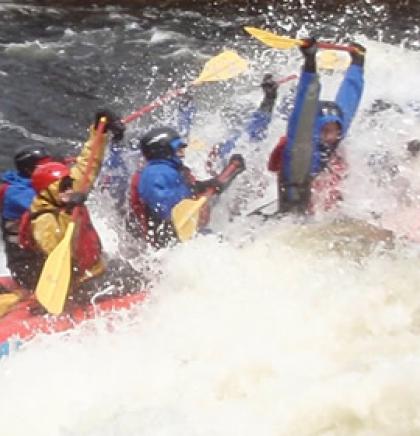 Paddles up overhead while hitting the white water