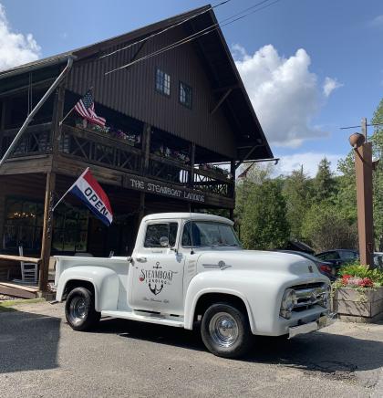 A white truck parked out front of the high peaked roof of Steamboat Landing