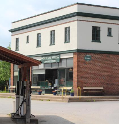 The exterior of a the two story brick and rendering building with gas pumps and ample parking.