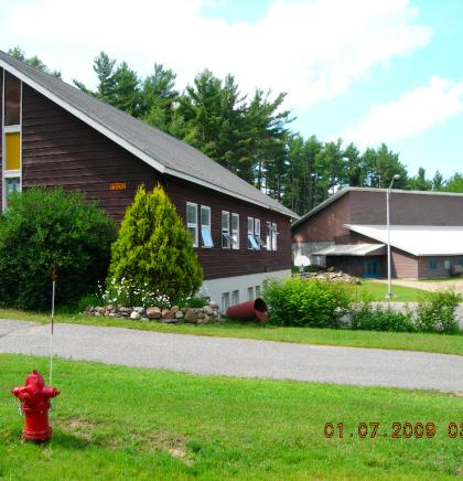 Exterior view of the lush grass and tall glass windows on the brown church.