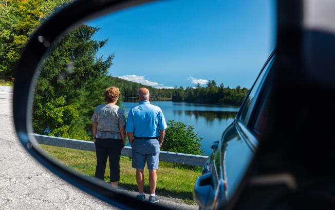 An older couple seen in a car mirror.