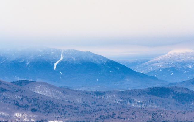 A mountain range covered in snow on a misty day.