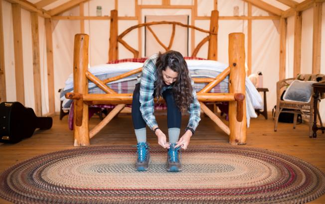 A person lacing up their boots in a cabin.