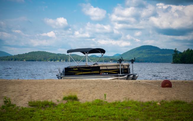 A boat sits on a beach on a lake.