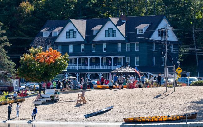 A classic hotel sits behind a town beach in a small town.