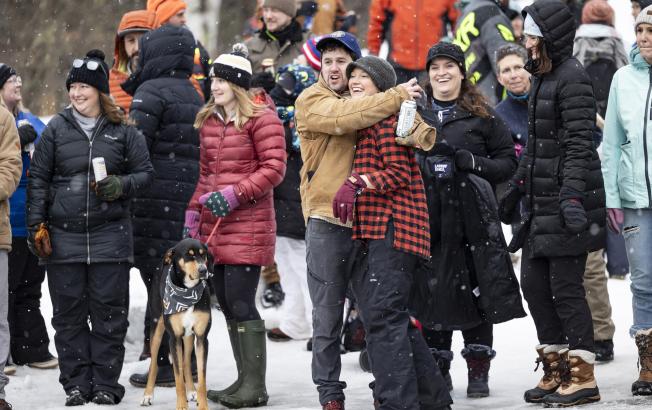 A group of people cheer at an outdoor winter carnival.