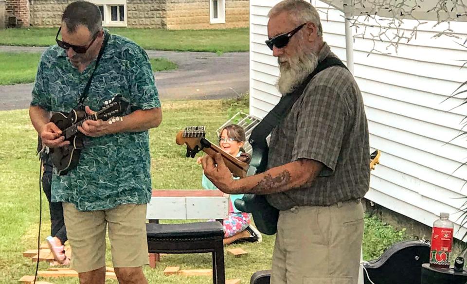 A photo of tim and norm playing their stringed instruments outside