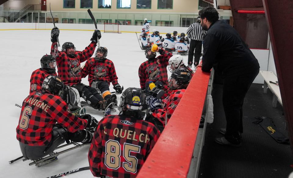 A synchronized ice skating team performs a routine in matching pink and black outfits