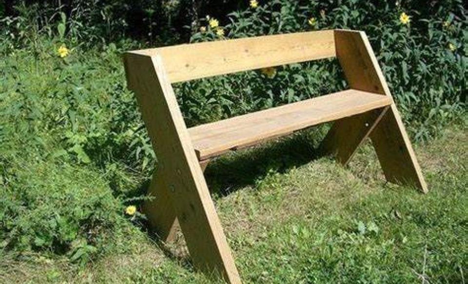 A leopold bench in a yard with green grass