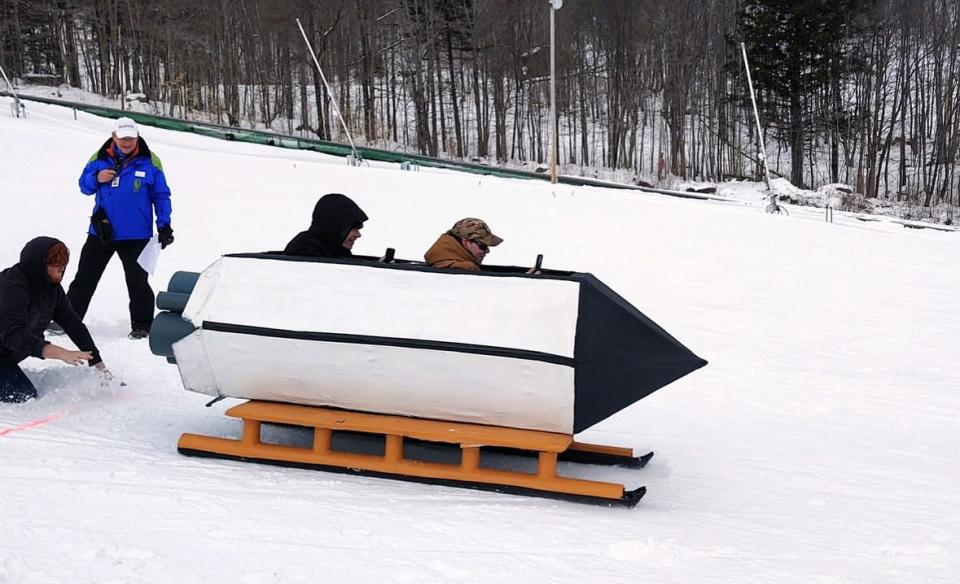 two people going down the hill in a rocketship sled