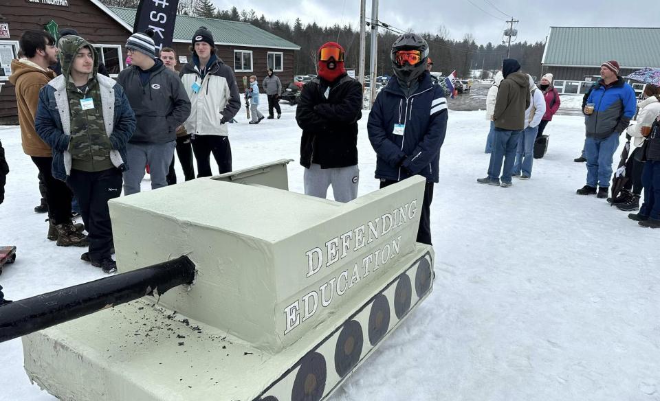 Two sledders standing next to their cardboard sled tank