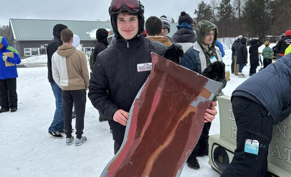 a boy holding up a sled that looks like a piece of bacon