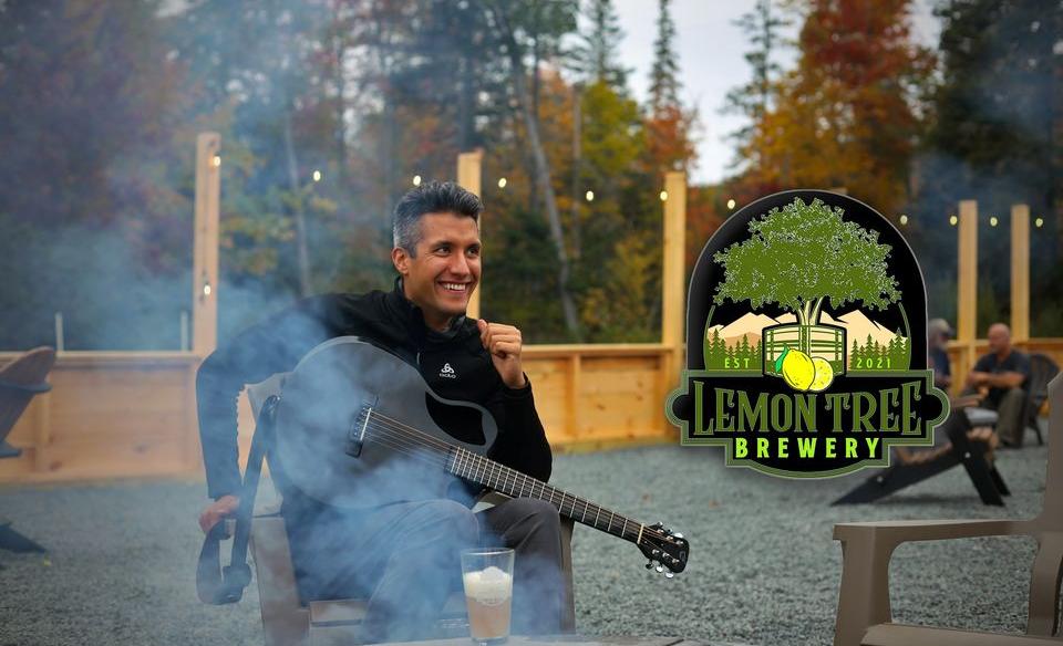 A phot of Kevin Alexander siiting in a chair out side of the Lemon Tree Brewery with his guitar