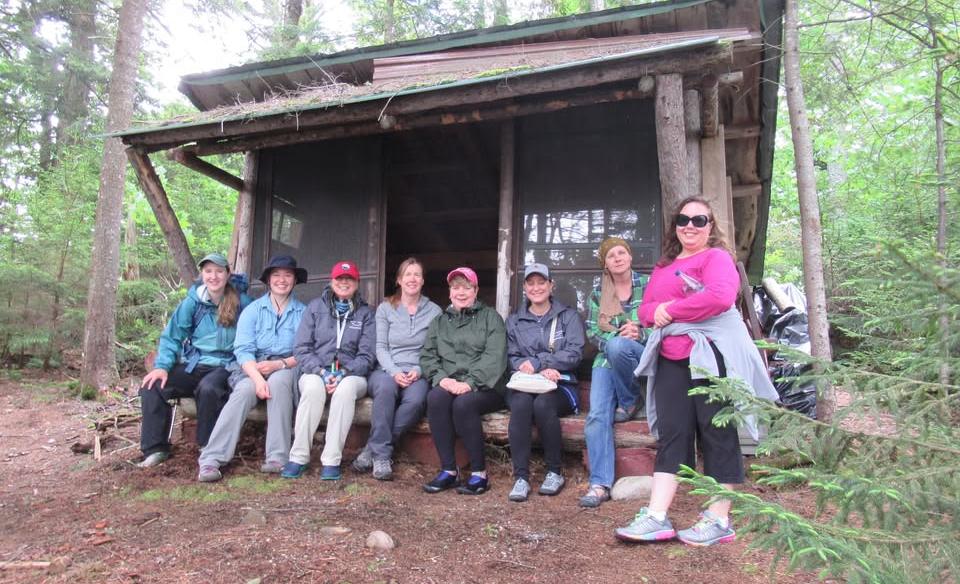 Several ladies sitting in a lean to for a group phot at great camp sagamore