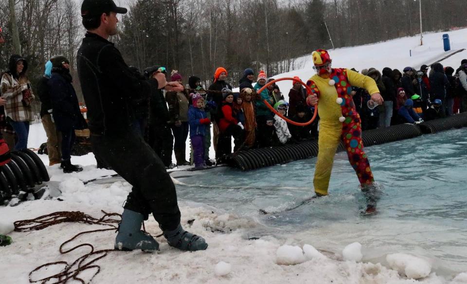 a person dressed as a clown being pulled out of the pool with a ring bouy