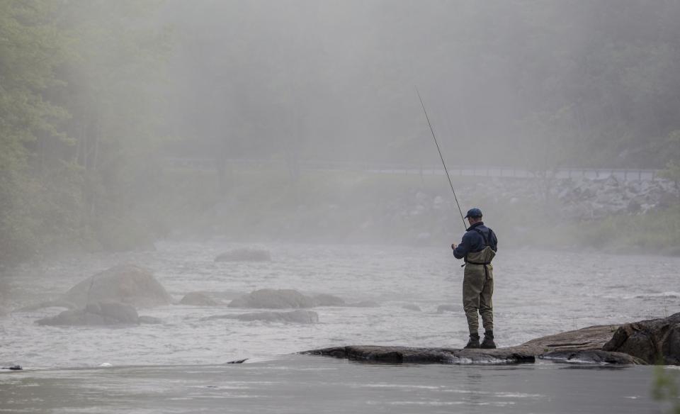 a person standing on a rock in a river fly sishing