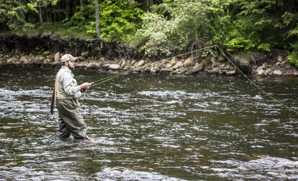 Man standing in a river dressed in waders and fly sishing