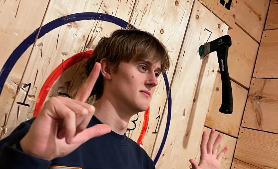 a young man standing in front of a bullseye with his axe in the upper corner