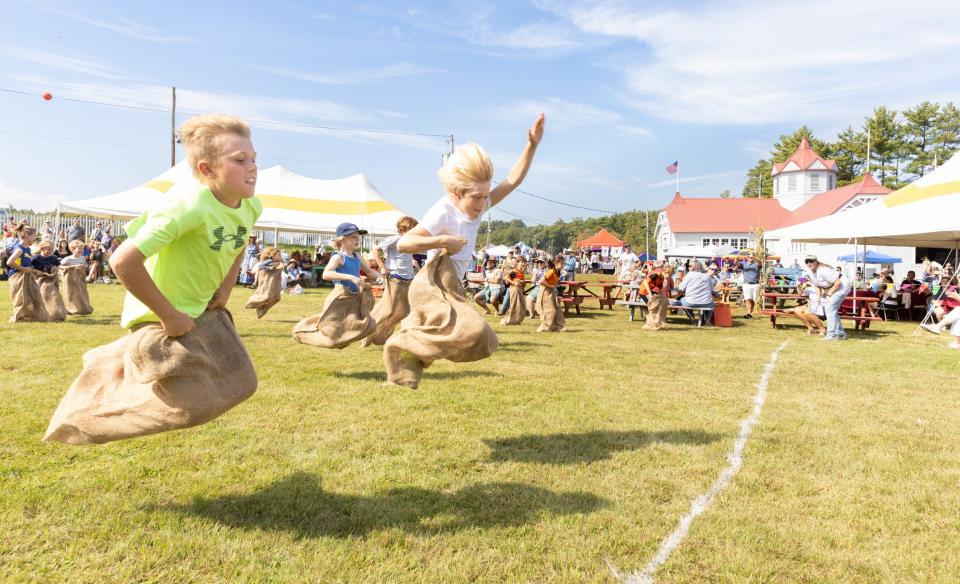 Kids cross finish line in sack races.