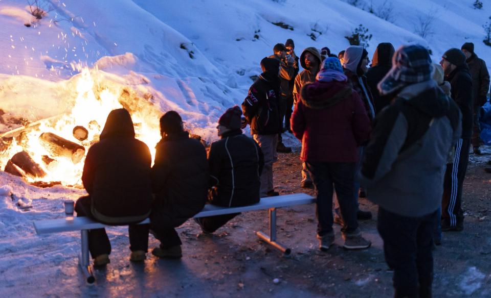 a group of people around a bon fire out in the snow