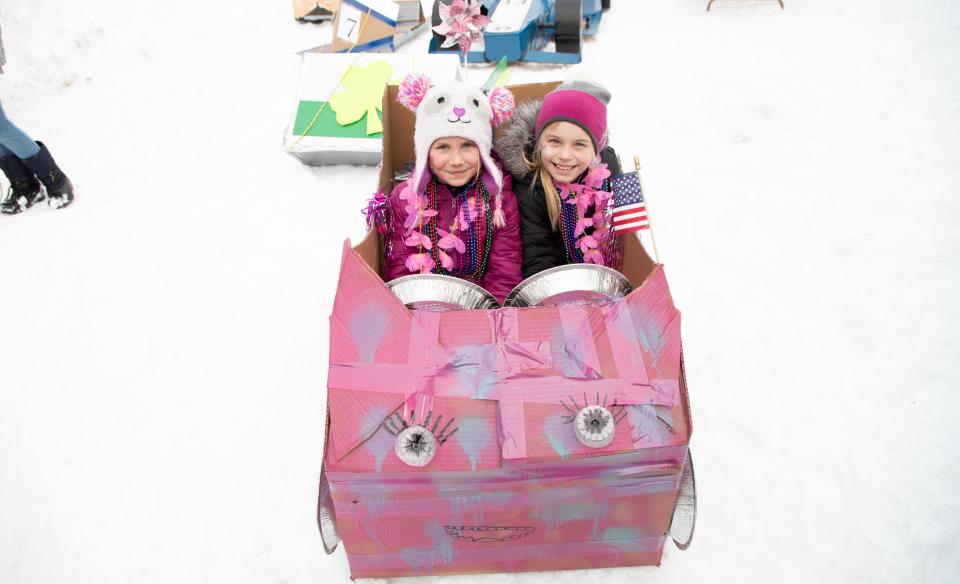 two girls in a pink cardboard sled