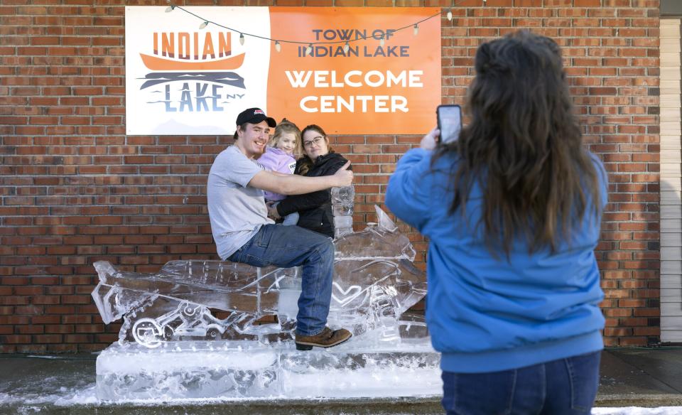 a woman taking a picture of people on the ice sculpted snowmobile