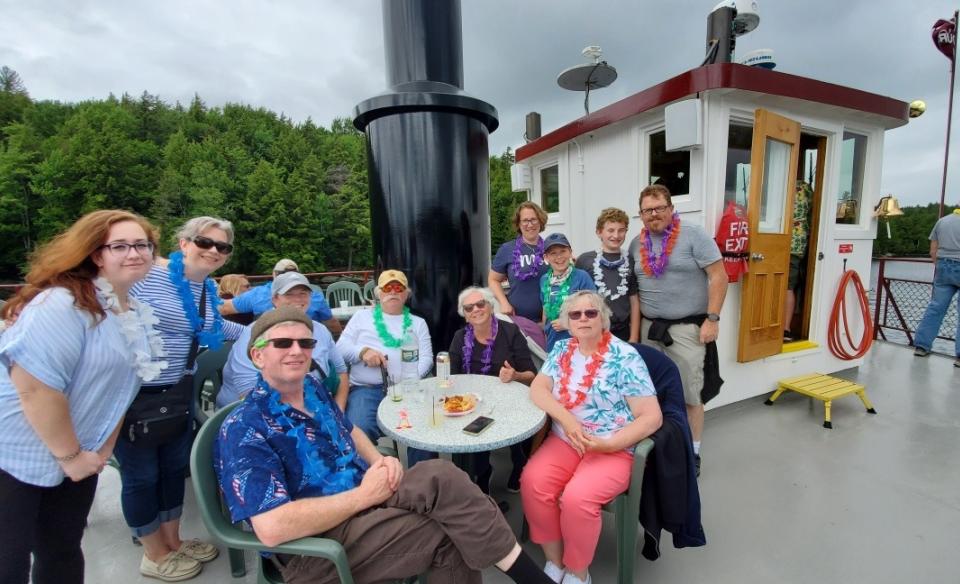 A group photo of several people on the top deck of the Durant dressed in their tropical shirts and weraring leis