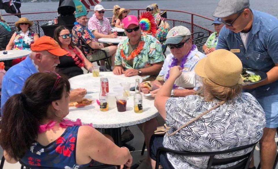 A view of the upper deck with people sitting at tables all dressed in their tropical attire