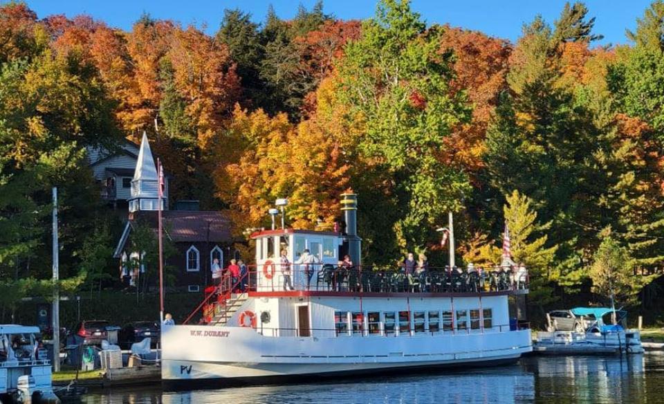 The WW Durant docked on shore with a backdrop of fall colored leaves on the trees behind it