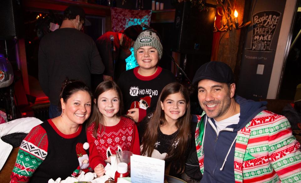 a familty all wearing ugly sweaters and sitting at a table together