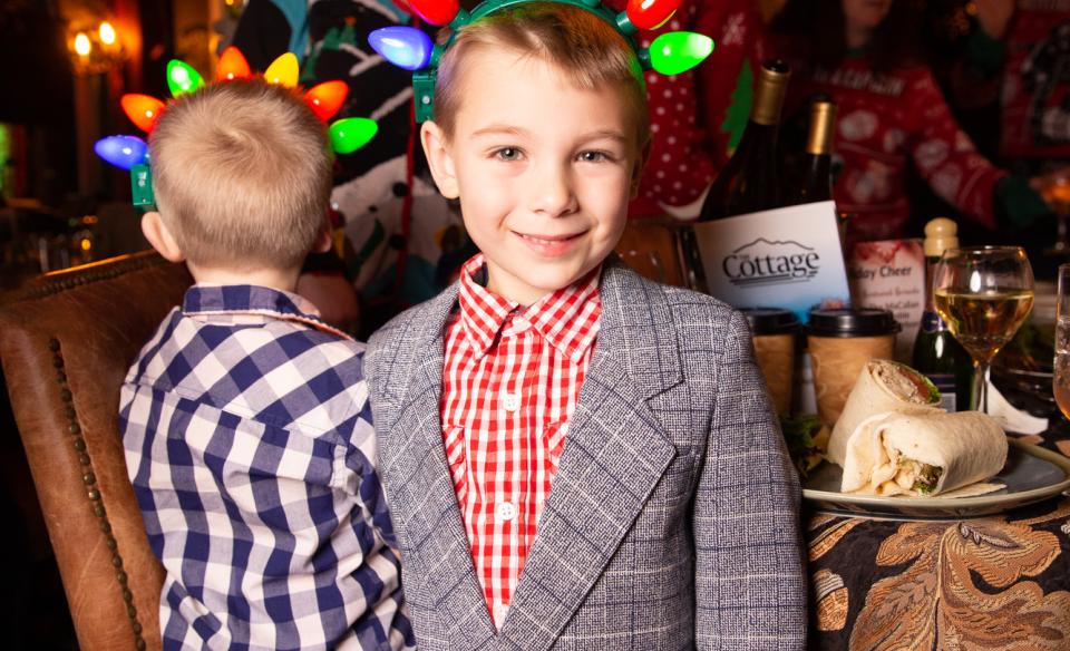 a little boy dressed up and has a head band of Christmas lights on his head