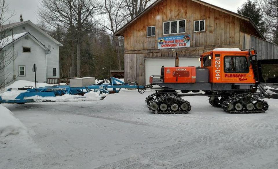 the outside of the pleasant riders garage with a snowmobile trail groomer