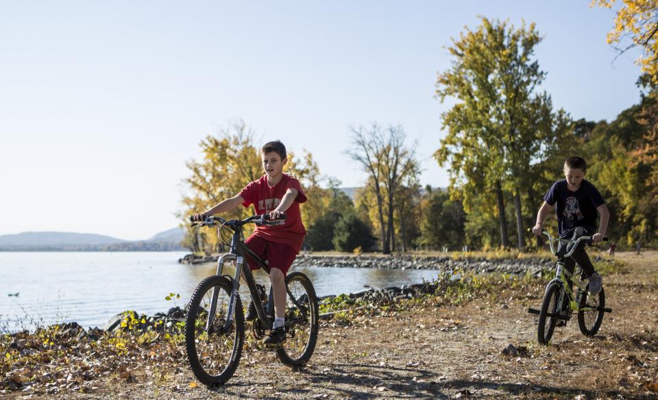 Two boys riding their bikes on a trail along a lake
