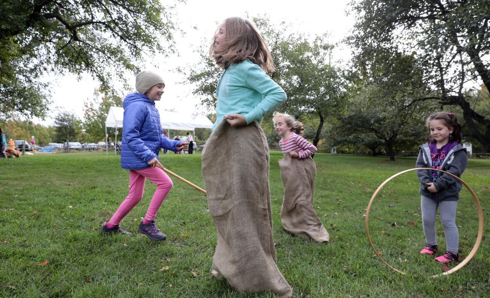 Several children playing outside with hula hoops and potato sack