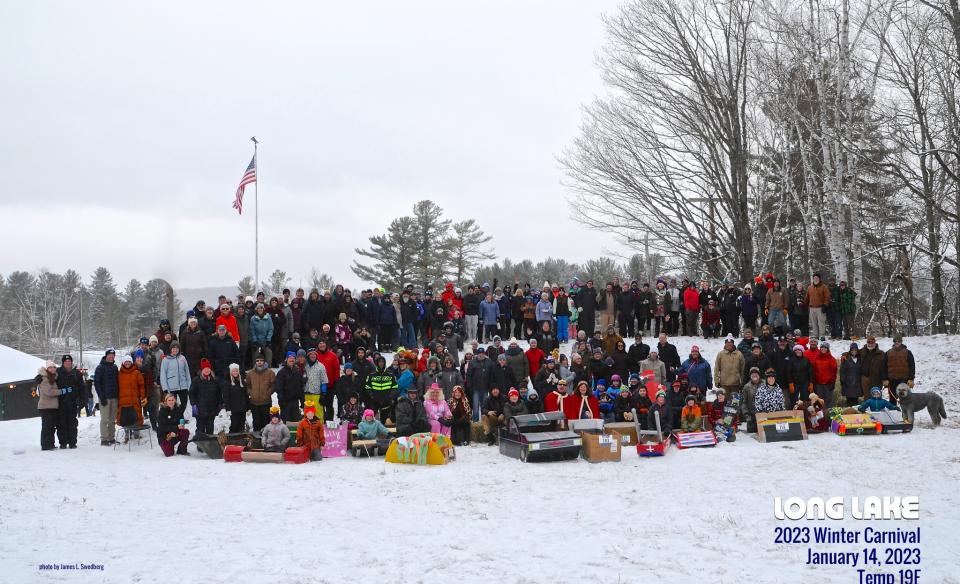 A large group of people who attended last year's carnival posing for a photo with cardboard sleds in front