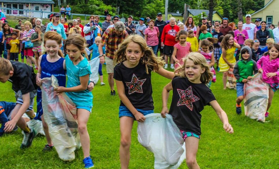 Many children in pairs doing a three-legged race