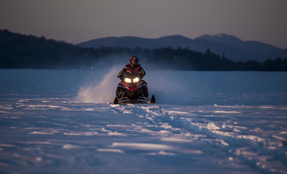 A person on a snowmobile travels across a snowy field